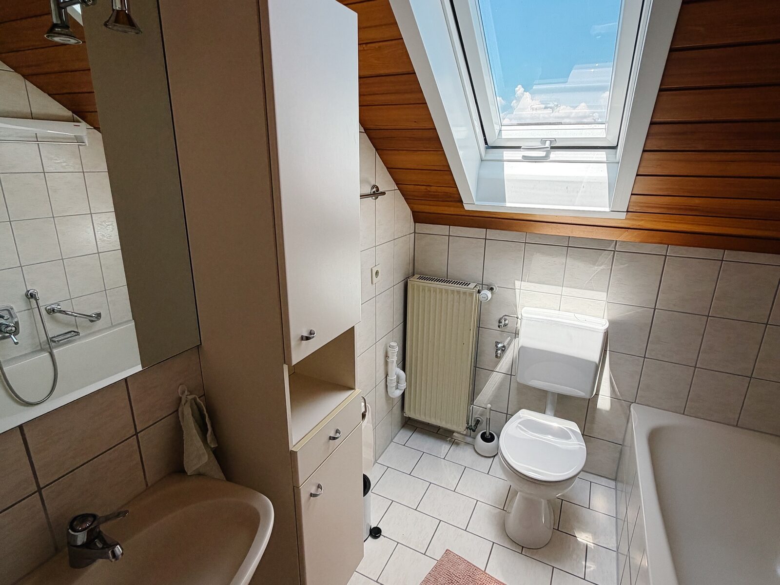 Helles Bad der Ferienwohnung mit Waschbecken, WC und großem Dachfenster
