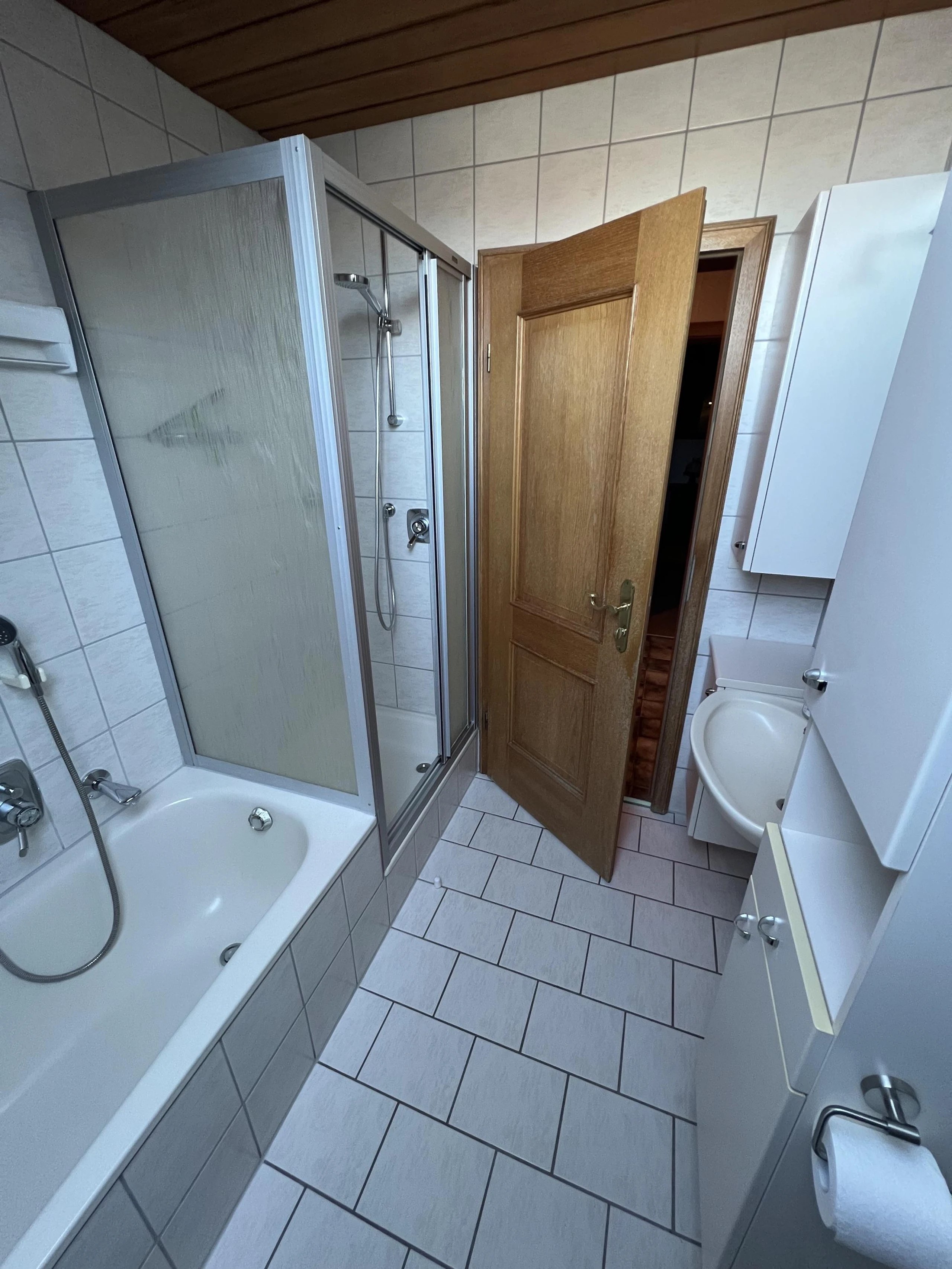 Modernes Bad der Ferienwohnung mit Dusche, hellen Fliesen, Dachfenster und funktionaler Ausstattung