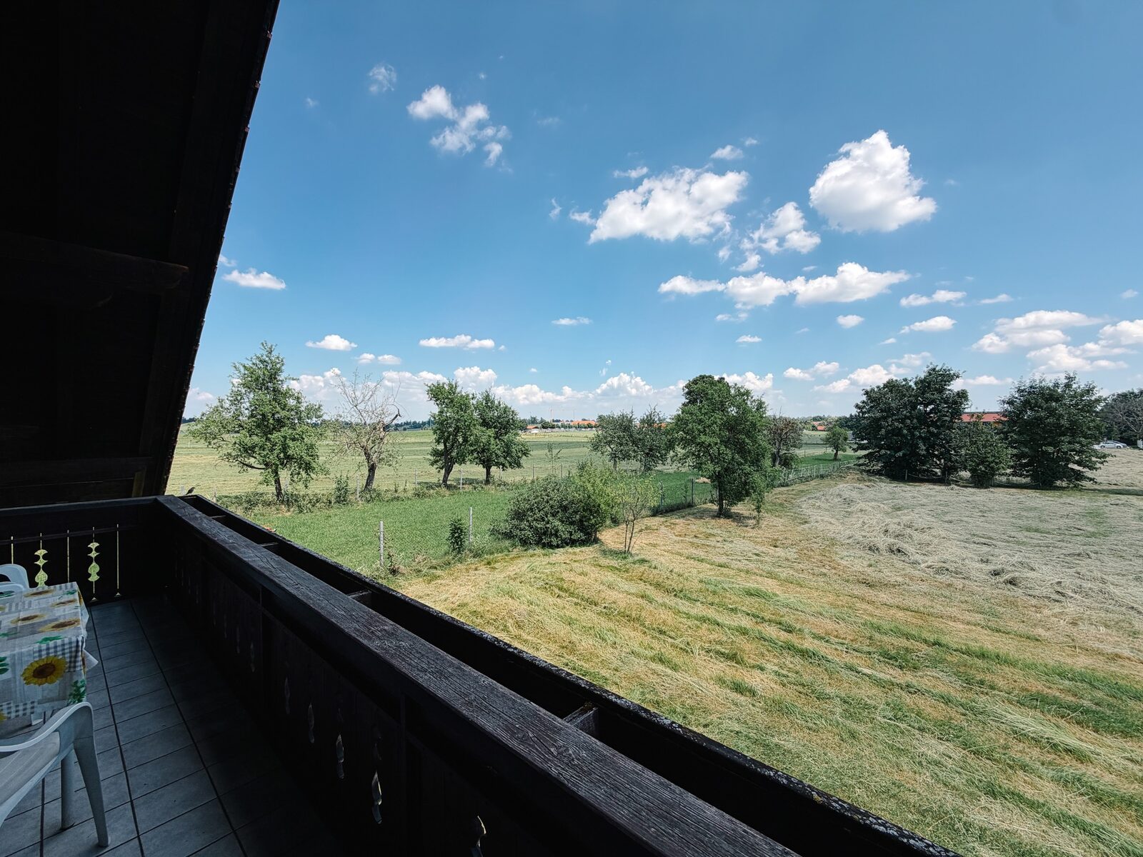 Überdachter Balkon mit weitem Blick über Wiesen und Obstbäume bei Uffing