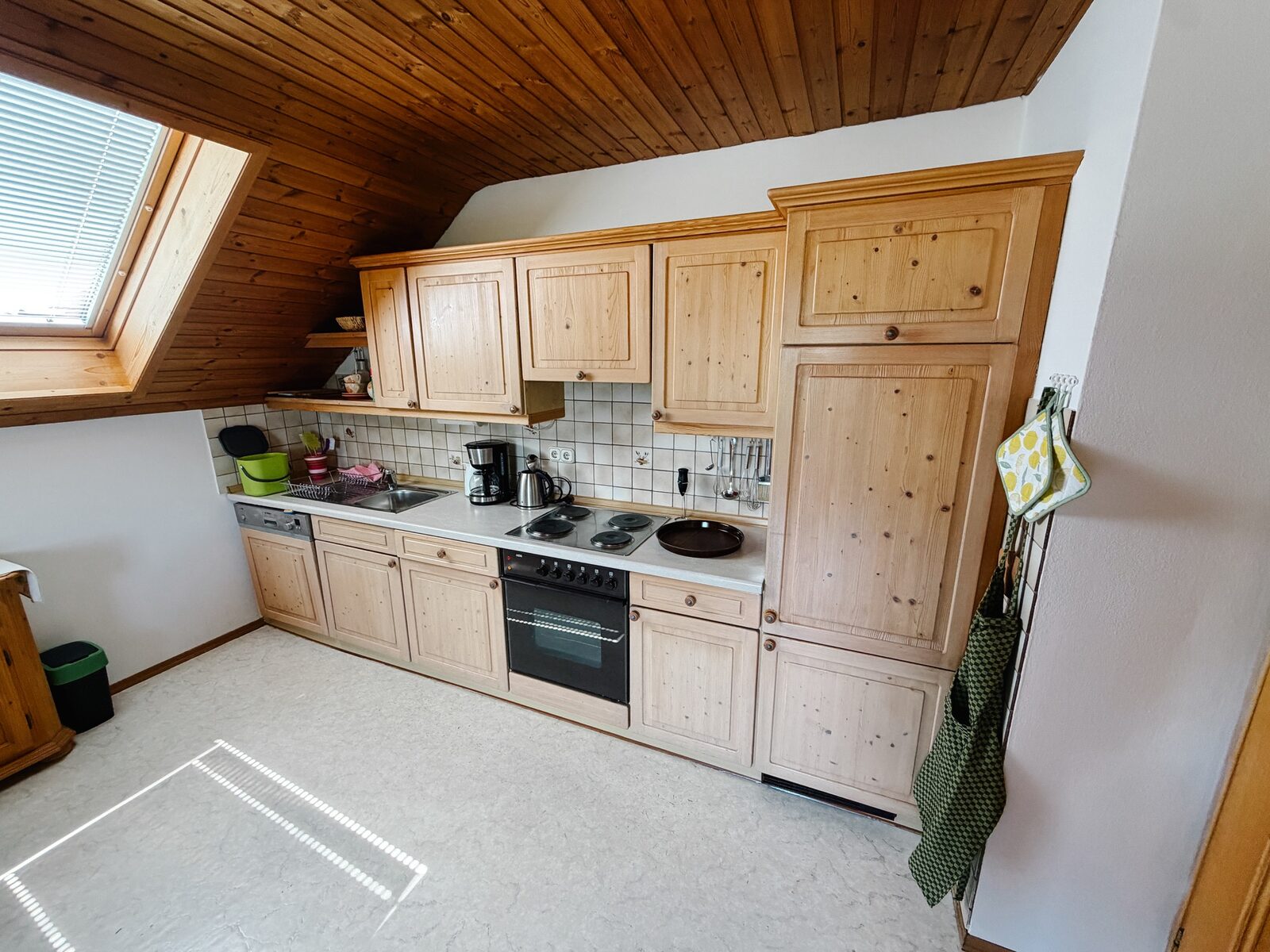Küchenzeile mit Holzfronten, Elektroherd, Backofen und Dachfenster
